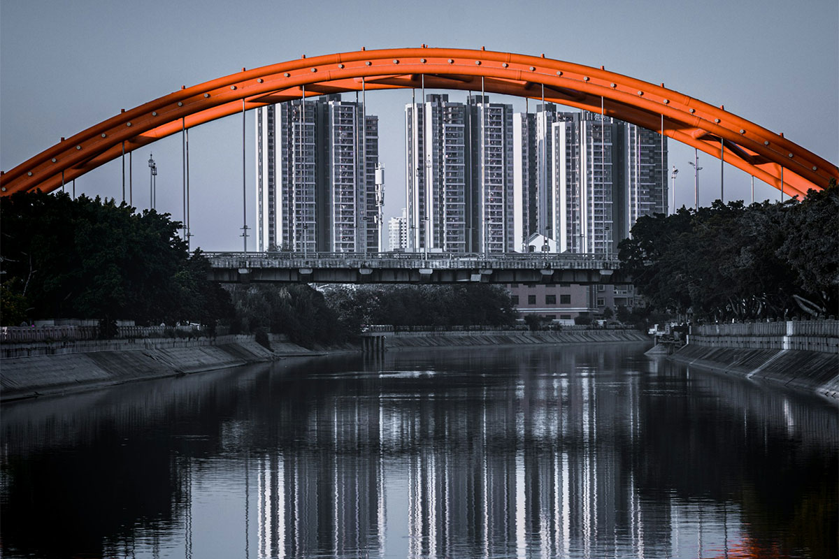 A bridge going over a river with buildings in the background.