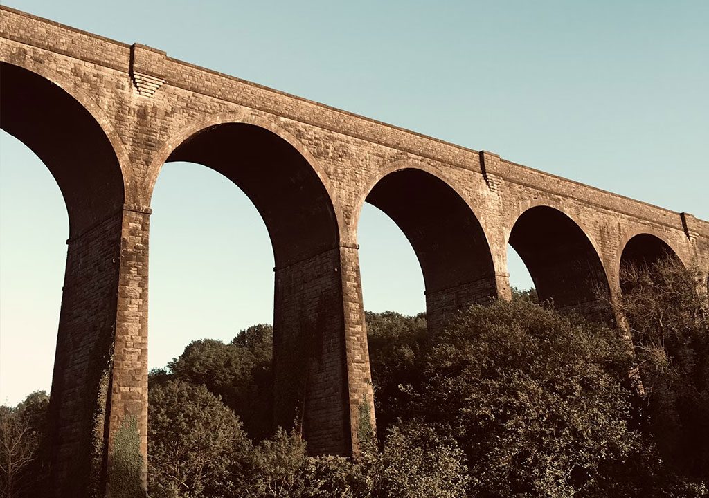 Tall stone bridge with arches over trees