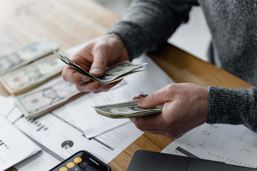 Person counting cash for their emergency savings plan