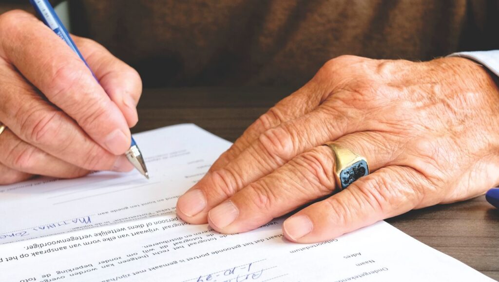 Older adult signing document during estate planning